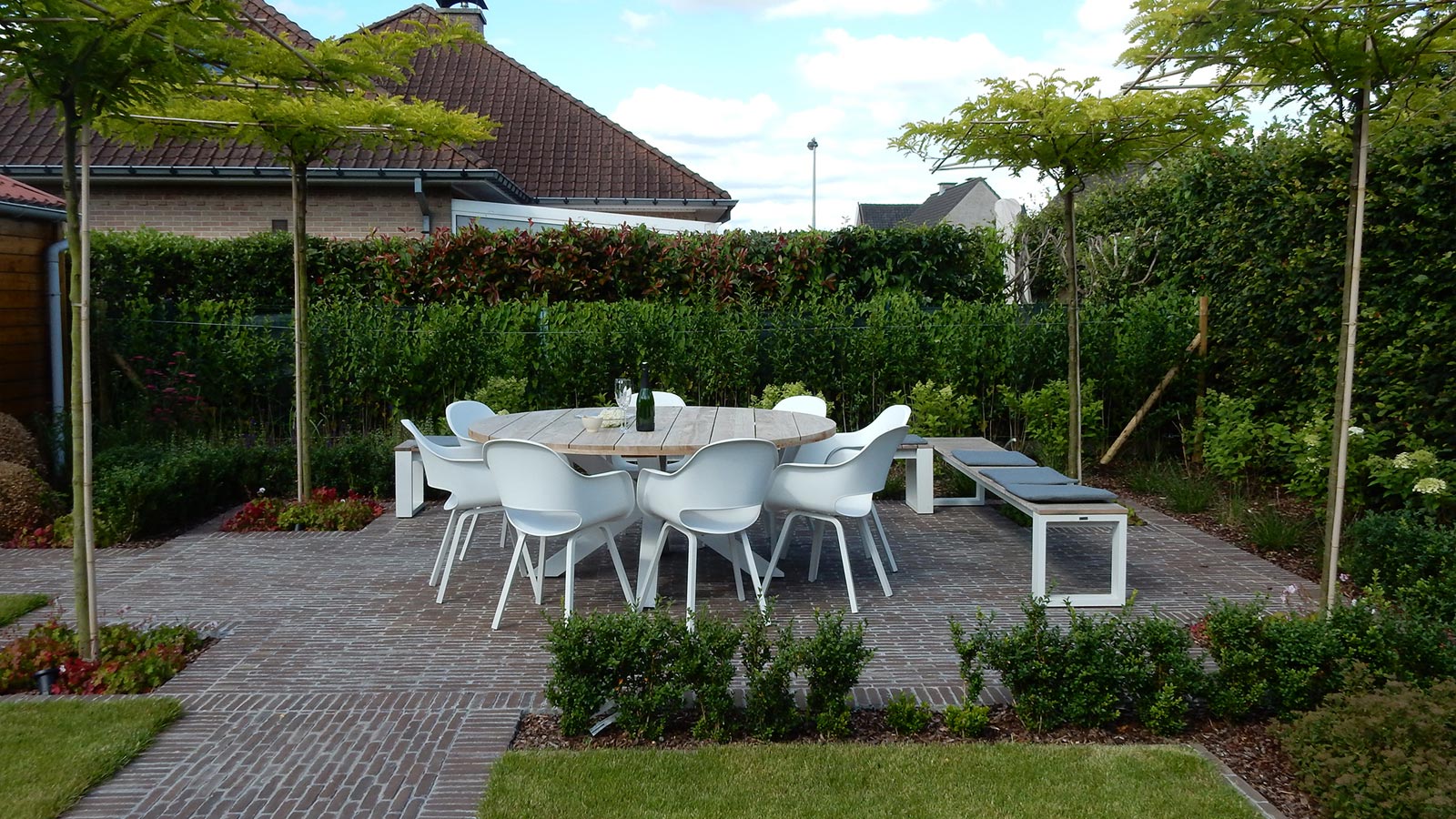 Witte design tuinstoelen met ronde houten tafel. 